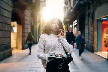 Cheerful black woman listening to music on street