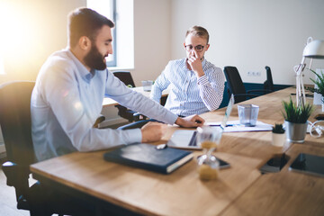 Obraz premium Professional caucasian 20s male colleagues having meeting to discuss planning and strategy for business partnership, skilled man employee talking with corporate owner share ideas for project