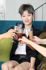 Young southeast asian woman group talk celebrate sing making funny mocking faces expression drinking cheering cheers on blue living room sofa