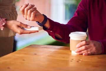 Close Up Of Man Making Contactless Purchase In Coffee Shop Using Smart Watch