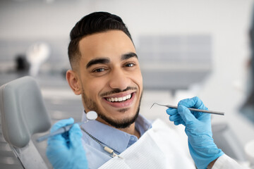 Portrait Of Happy Arab Man Sitting At Dentist Chair In Modern Clinic