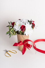 Floral arrangement in paper cup. Gift for Woman's Day or Valentine's Day. Red roses and white chrysanthemums