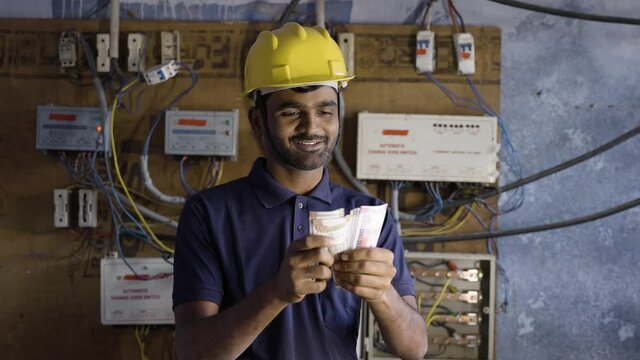 smiling electrician couting money - concept of payment after completion of work, successful career and happiness