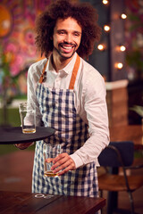 Portrait Of Smiling Male Server Clearing Table In Cool Bar Or Club © Monkey Business
