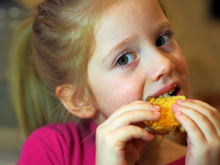 Cute blonde girl eats cookies. Sweets for children.