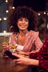 Female Friends Meeting And Talking At Table In Bar