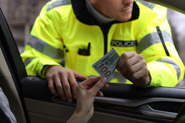 Woman giving bribe to police officer out of car window, closeup