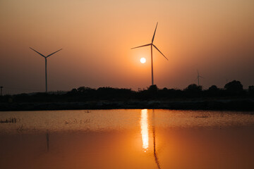 View of the sunset at the lake with windmills on the hills at Wankaner, Gujarat, India