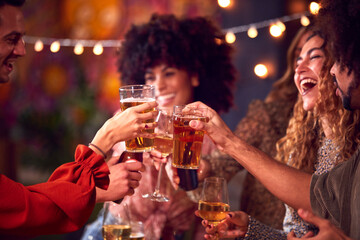 Multi-Cultural Group Of Friends Enjoying Night Out Drinking In Bar Together Making A Toast