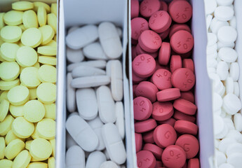 Four packages with multi-colored pills close-up.