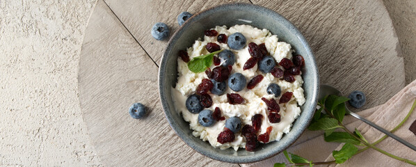 a bowl of cottage cheese with blueberries and cranberries on a light table