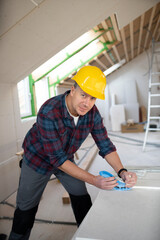 man on building site with yellow helmet works in drywall construction