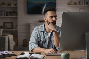 Man working with computer at table in home office