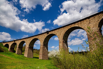Obraz na płótnie Canvas Old railway stone viaduct in the spring in sunny day.