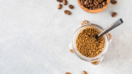 A jar with instant coffee and a spoon inside top view. Copy space.