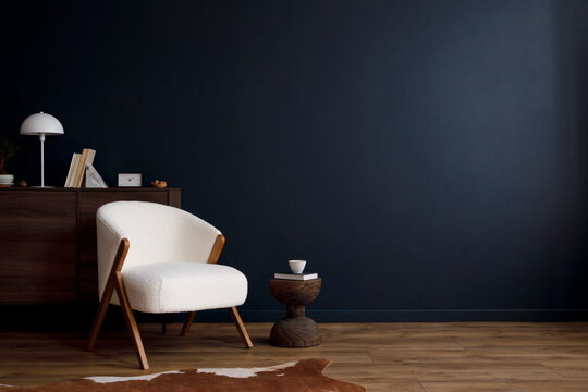 Modern living room interior composition with fluffy armchair, wooden commode and modern home accessories. Blue wall. Template. Copy space. Home staging.