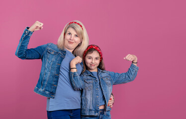 Smiling mother and daughter showing muscles in studio