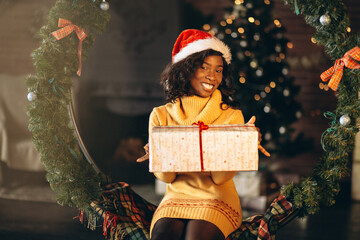 African american woman sitting and holding christmas present