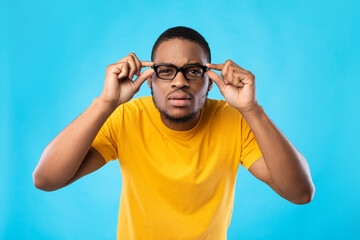 Black Guy In Glasses Squinting Eyes Posing Over Blue Background