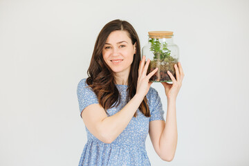 Woman is holding a terrarium and smiling. Caring for plants at home. Green terrarium. plant in...