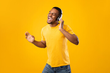 Black Guy Singing Wearing Headphones And Dancing Over Yellow Background