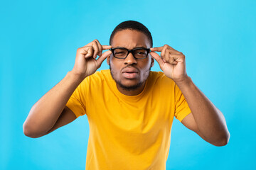African American Guy With Poor Eyesight Squinting Eyes, Blue Background