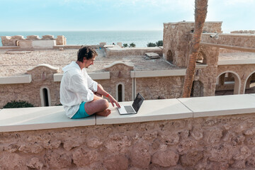 freelancer with a laptop in his hands works on vacation