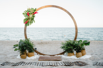 Wedding ceremony Wedding round arch decorated with flowers and vases with greenery Outdoors Sea...