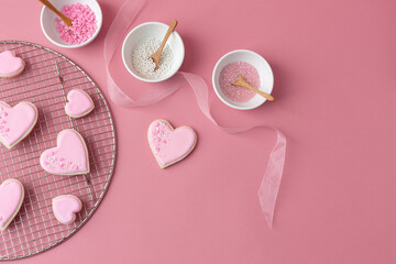 Heart-Shaped Valentine Cookies Decorated with Pink Icing; Bowls of Sprinkles; Pink Background