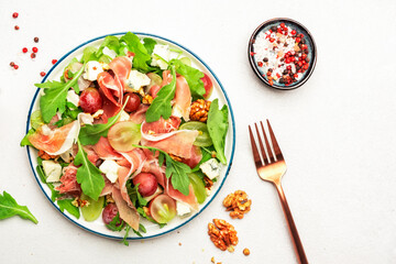 Freash grape salad with jamon, blue cheese, arugula, nuts on white table background, top view, copy space