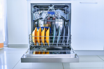 Open dishwasher with shiny clean dishes in a white home kitchen