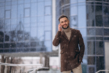 Young handsome business man using phone outside the business center