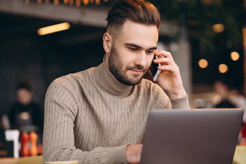 Handsome business man working on computer and drinking coffee in a cafe