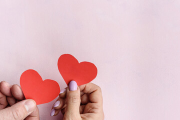 Fototapeta premium red heart made of paper in the hands of a man and a woman. Copy space.