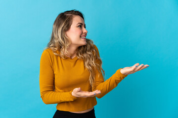 Young Brazilian woman isolated on blue background with surprise expression while looking side