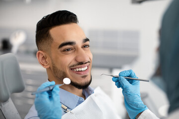 Closeup Of Happy Middle-Eastern Male Patient Getting Dental Treatment In Modern Clinic