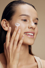 brunette with moisturizer on the cheeks in the eye area close-up make-up