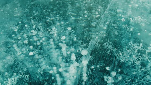 Thick layer of blue frozen water with bubbles and cracks on the lake