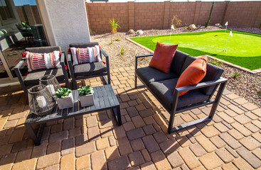 Fototapeta na wymiar Rear Yard Pavers Patio With Table, Chairs And Couch With Decorative Pillows