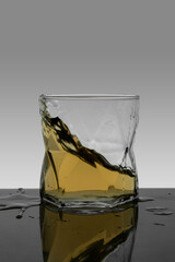 vertical portrait splash of whiskey in crystal glass with gradient background