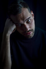 portrait of a young man with his head resting on his fist looking very bored and depressed