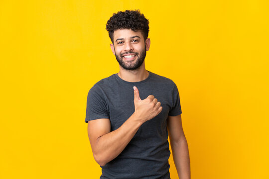 Young Moroccan man isolated on yellow background giving a thumbs up gesture
