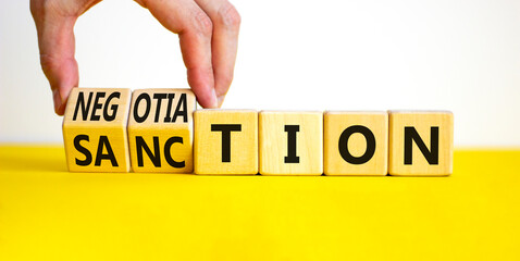 Sanction or negotiation symbol. Businessman turns cubes, changes the word sanction to negotiation....