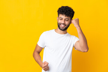 Young Moroccan man isolated on yellow background celebrating a victory