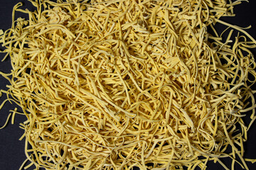Egg noodles on a black background. A bunch of dry noodles on a dark background. pasta