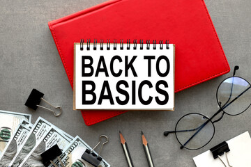 Back to Basics text on open notepad on red notepad on gray background