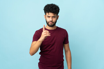 Young Moroccan man isolated on blue background frustrated and pointing to the front