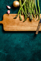 Asparagus, onion and garlic over cutting board. Food ingredients concept. Copy space, studio shot.