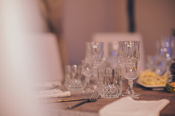 Empty crystal glasses on house dinner table. Restaurant, banquet setting with crystal glasses