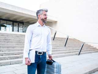 Businessman with laptop and suitcase on street